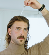 Man applying Lumazen Revitalizing Edelweiss Hair Tonic to his scalp with the pipette