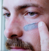 Man applying Lumazen Soothing Detox Edelweiss Night Cream under his eye with a fingertip