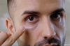Man applying Lumazen Nourishing Edelweiss Eye Cream under his eye with a fingertip