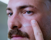 Man applying Lumazen Anti-Aging Edelweiss Day Cream to his cheek with a fingertip